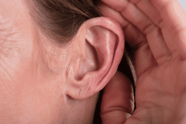 Eine Person hält sich die Hand ans Ohr, um besser hören zu können (Foto: AndreyPopov/Getty Images Pro via Canva).